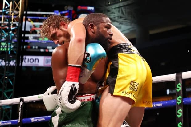 Logan Paul is draped over Floyd Mayweather during their exhibition fight in Miami on Sunday. (Getty Images - image credit)