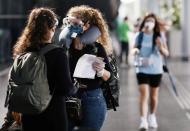 People wear protective face masks at international arrivals area at Guarulhos International Airport, amid coronavirus fears, in Guarulhos