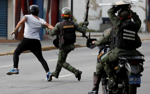 Security forces run after a demonstrator during a protest of opposition supporters against Venezuelan President Nicolas Maduro's government in Caracas - Credit: &nbsp;Carlos Garcia Rawlins/&nbsp;REUTERS