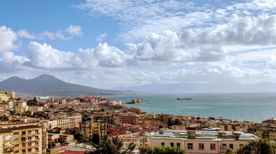 Naples s a popular travel destination in Italy but it also is a place where "Ripley" was filmed. 
pictured: a view of Naples coast, central areas and surrounding mountains on a cloudy day