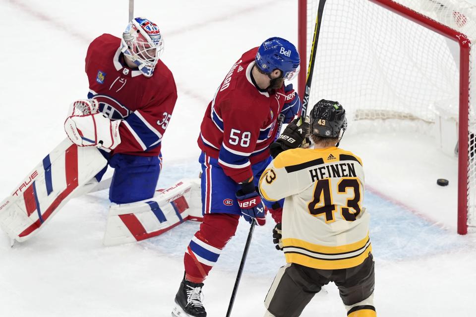 Boston Bruins' Danton Heinen (43) scores against Montreal Canadiens' Sam Montembeault (35) as David Savard (58) watches during the first period of an NHL hockey game Saturday, Jan 20, 2024, in Boston. (AP Photo/Michael Dwyer)