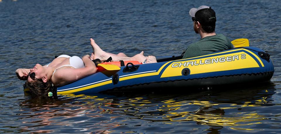 Beth Derderian of Framingham dips her head in the cool waters of Lake Cochituate while out on a small inflatable boat with her boyfriend, James Jones, also of Framingham,  as the temperature reaches 80 degrees, May 13, 2022. The boat was a birthday present from Derderian to her boyfriend, whose birthday is May 13th.  
