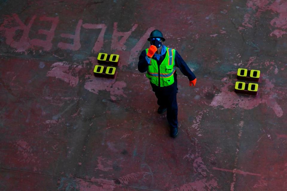 Longshoreman Clyde Sands communicates with the gantry operator as they work to offload a cargo ship at PortMiami on Saturday, February 20, 2021. Sands, a ship flag, has been working as a longshoreman for 28 years.