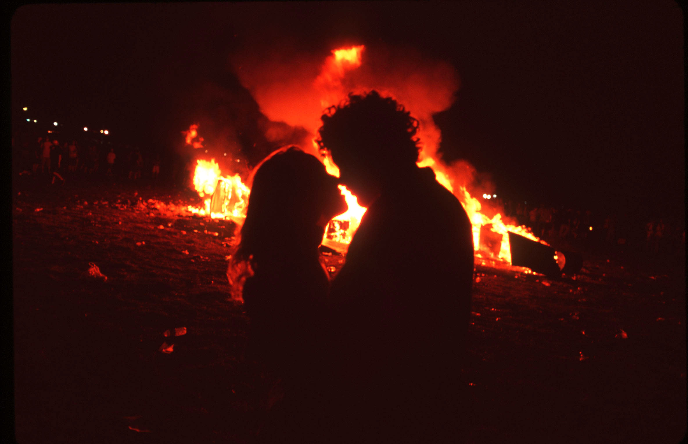 A silhouette of two people in front of a fire.