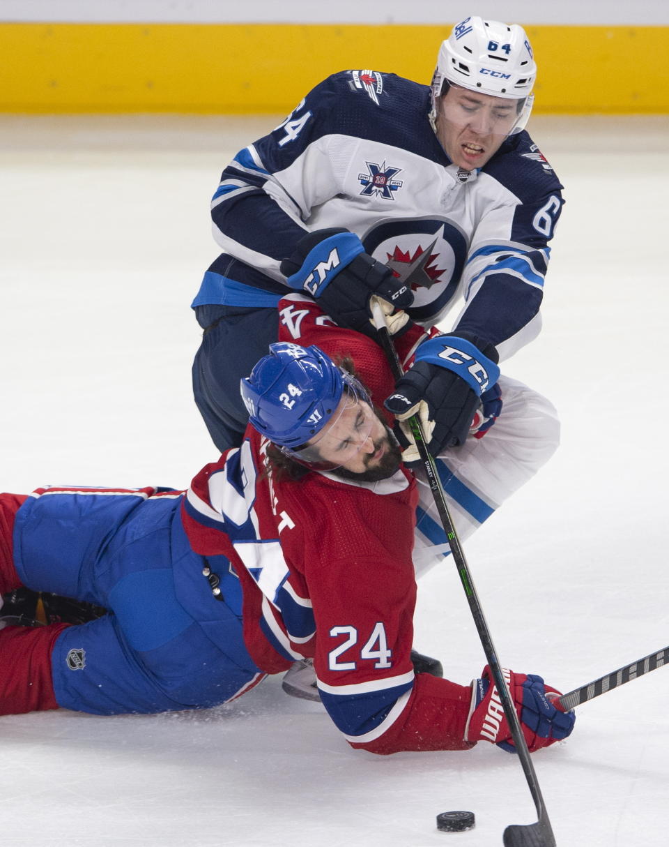 Montreal Canadiens' Phillip Danault (24) falls to the ice as he battles for a loose puck with Winnipeg Jets' Logan Stanley (64) during the first period of an NHL hockey game, Thursday, April 8, 2021 in Montreal. (Ryan Remiorz/The Canadian Press via AP)