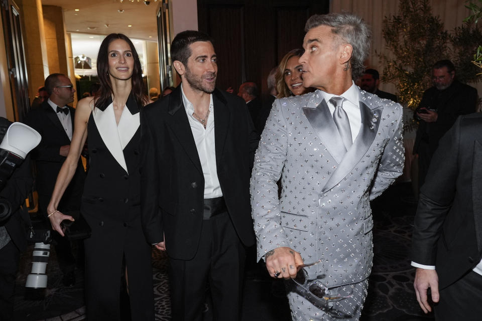 Jeanne Cadieu, de izquierda a derecha, Jake Gyllenhaal y Robbie Williams llegan a la 82ª edición de los Globos de Oro el domingo 5 de enero de 2025 en el Beverly Hilton de Beverly Hills, California. (Foto AP/Chris Pizzello)