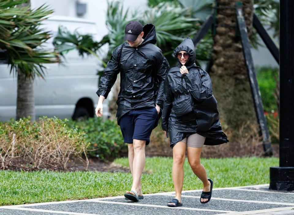 A couple tourist from Poland David Kryczka, and Justina Ciapinska walk by A1A/Collins Ave on Thursday, Dec. 14, 2023 in Bal Harbour, Fla. The gusty winds, heavy rain, flooded streets and other hazards are expected continue over the weekend in Miami, Fort Lauderdale and Palm Beach.