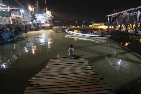 Kyaw Khine Soe, 16, rests on a dock after finishing his shift at San Pya fish market, in Yangon, Myanmar February 16, 2016. REUTERS/Soe Zeya Tun