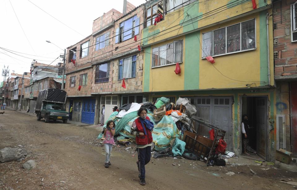 Vecinos que necesitan comida colocaron trozos de tela roja en sus ventanas para alertar a empleados del Ayuntamiento, que reparten bolsas de alimentos gratis para los necesitados durante una cuarentena para combatir la expansión del coronavirus, en Bogotá, Colombia, el miércoles 27 de mayo de 2020. (AP Foto/Fernando Vergara)