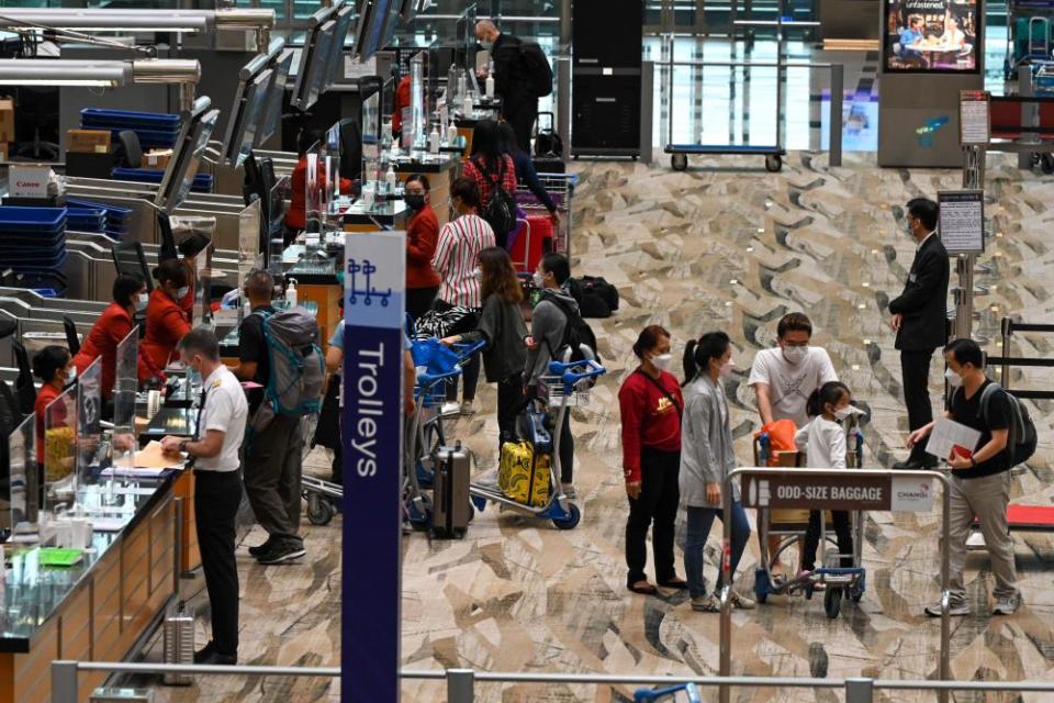 Travellers at a check-in counter at Changi airport in Singapore