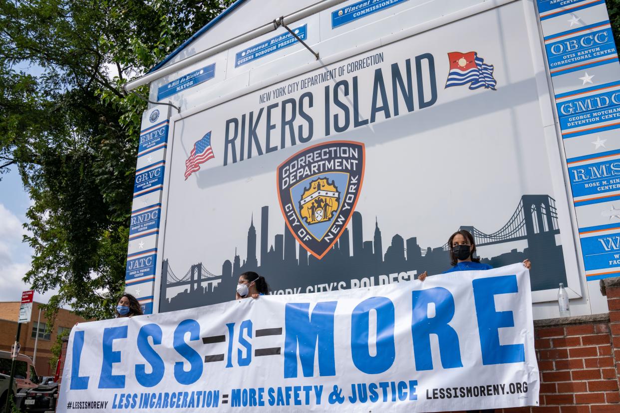Criminal justice reform advocates holding up a sign for "Less is More" legislation outside the entrance to Rikers Island in Queens, New York.