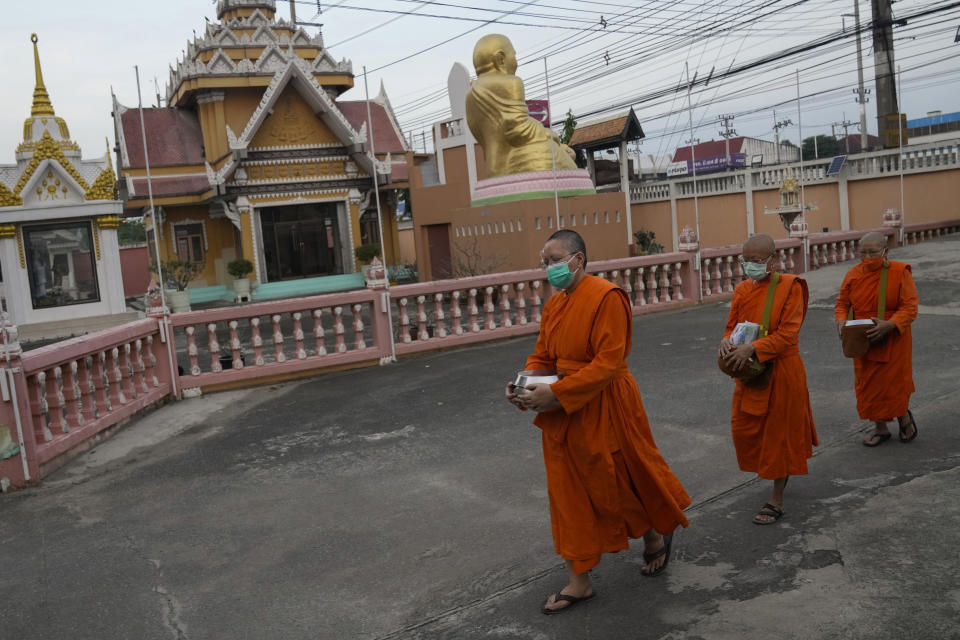 From left, Bhikkhuni Dhammavanna, Bhikkhuni Dhammaparipunna and Bhikkhuni Dhammasumana walk back to the Songdhammakalyani temple in Nakhon Pathom province on Sunday, Nov. 21, 2021. (AP Photo/Sakchai Lalit)