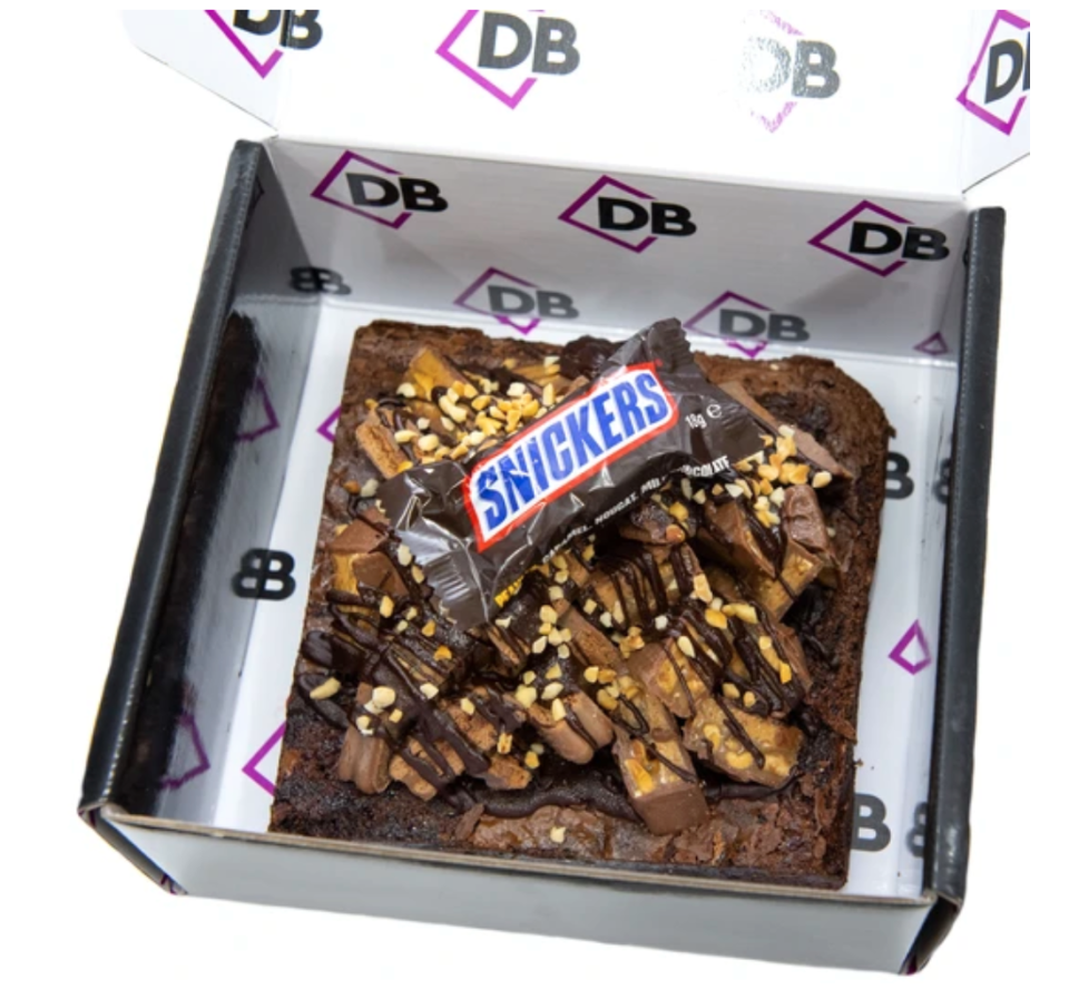 A giant brownie topped with Snickers bars and TimTams