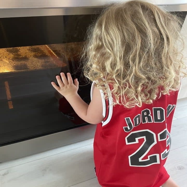 author's daughter watching cookies bake