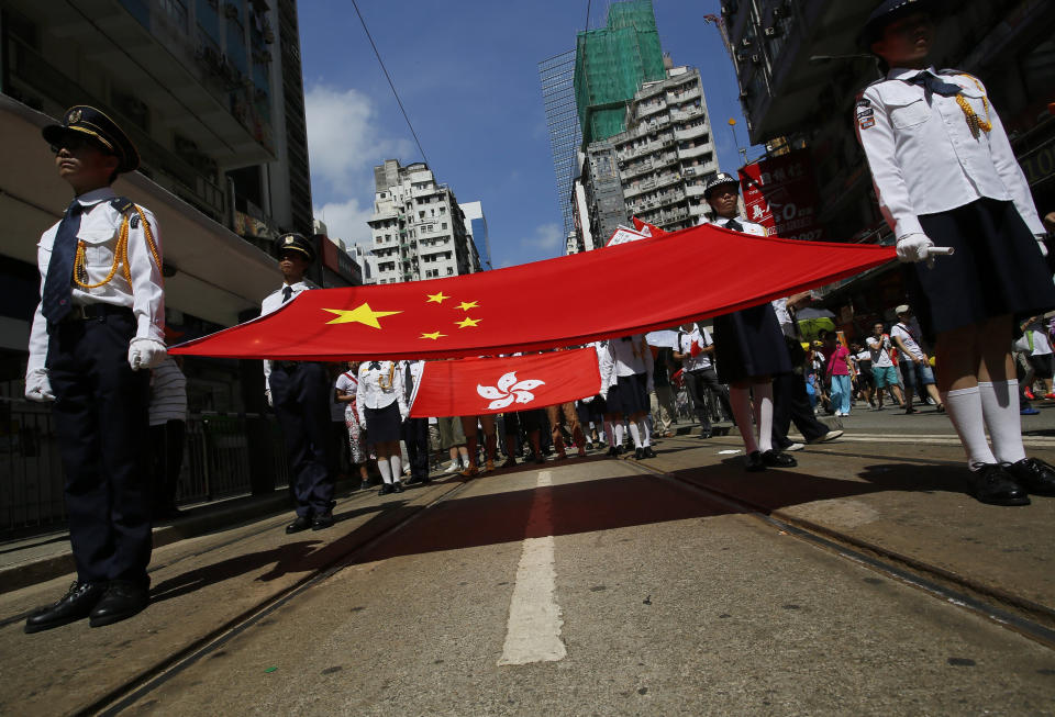 FILE - In this Sunday, Aug. 17, 2014, file photo, participants hold a Chinese national flag and a Hong Kong flag as tens of thousands of people march on a down town street to oppose a planned civil disobedience campaign by pro-democracy activists in Hong Kong. A year after Beijing imposed a harsh national security law on Hong Kong, the civil liberties that raised hopes for more democracy are fading.(AP Photo/Vincent Yu, File)