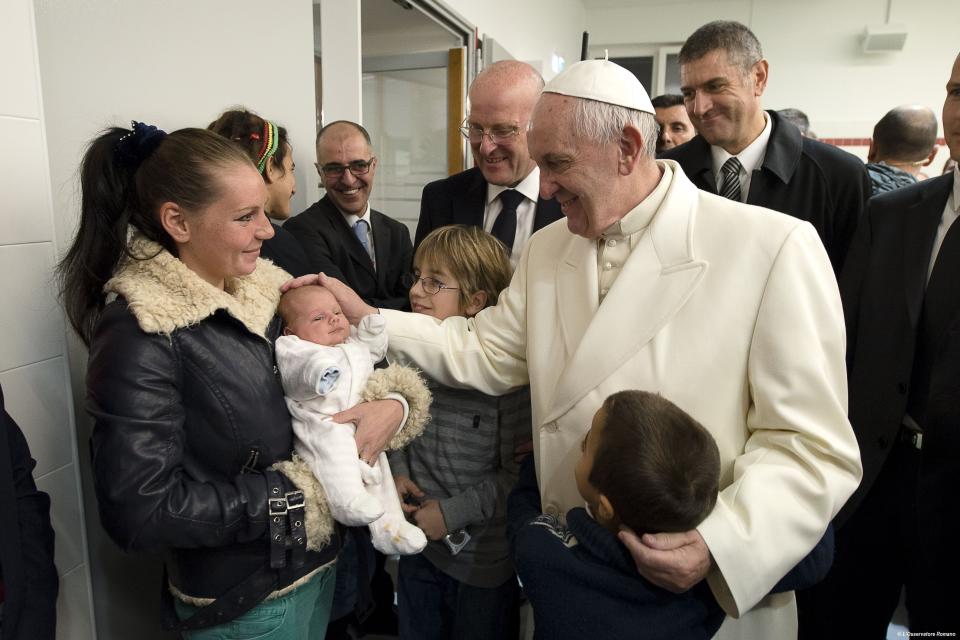 FILE -- In this Dec. 18, 2015 file photo Pope Francis caresses a baby at a charity, in Rome. The pontiff on Wednesday, Aug. 19, 2020, during his weekly audience in the Apostolic palace at the Vatican, warned against any prospect that rich people would get priority for a coronavirus vaccine. (L'Osservatore Romano/Pool Photo via AP)