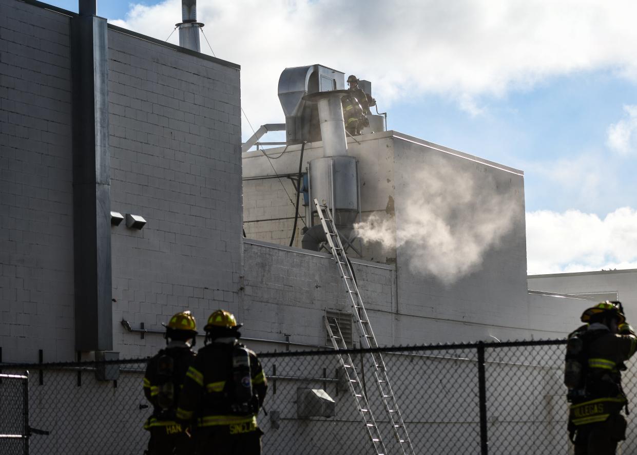 Members of the Lansing Fire Department work at the scene of a structure fire Tuesday, Aug. 9, 2022, near the intersection of North Larch Street and East Michigan Avenue.