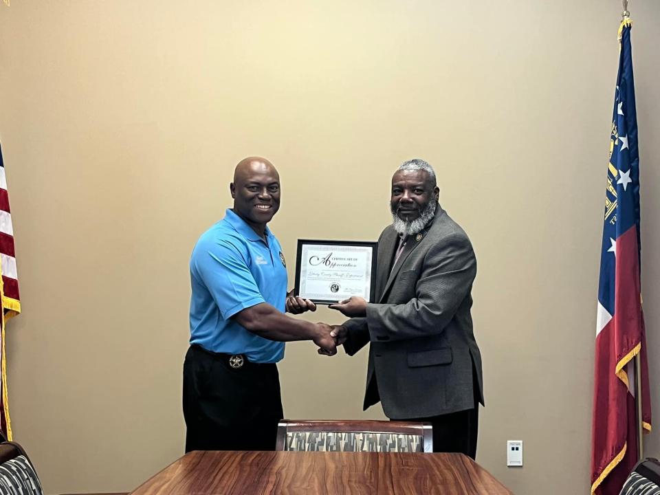 Liberty County Sheriff William Bowman (left) receives a plaque from Andrew Williams of The Eleven Black Men of Liberty County. Bowman competed in a charity golf tournament to benefit the organization.