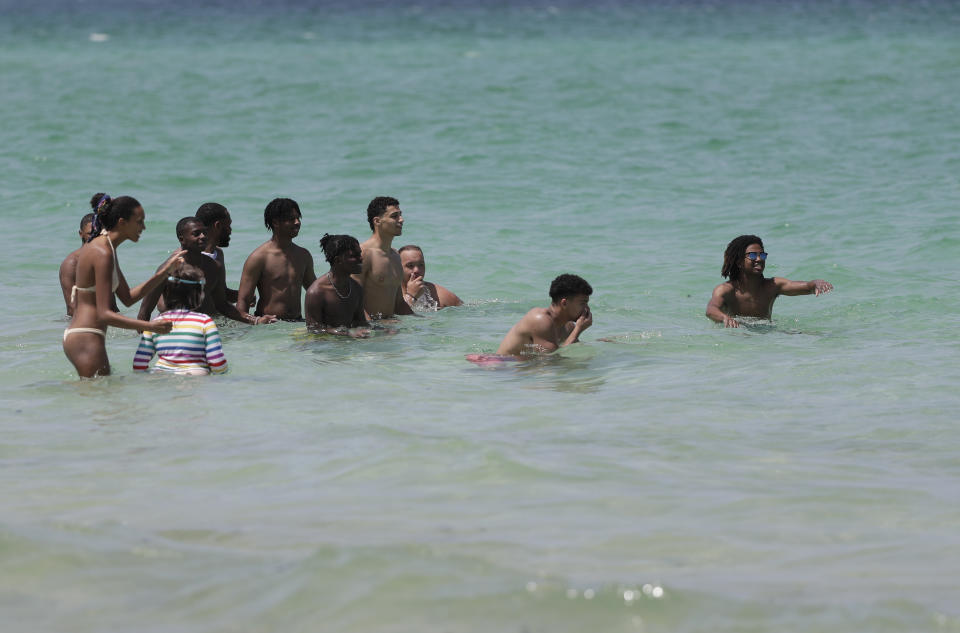Beach goers pause and watch as a large marine animal passes near them as they enjoy a day at the beach, Tuesday, June 30, 2020, on Miami Beach, Florida's famed South Beach. Beaches in Miami-Dade County will be closed from Friday, July 3 through Monday, July 6. (AP Photo/Wilfredo Lee)