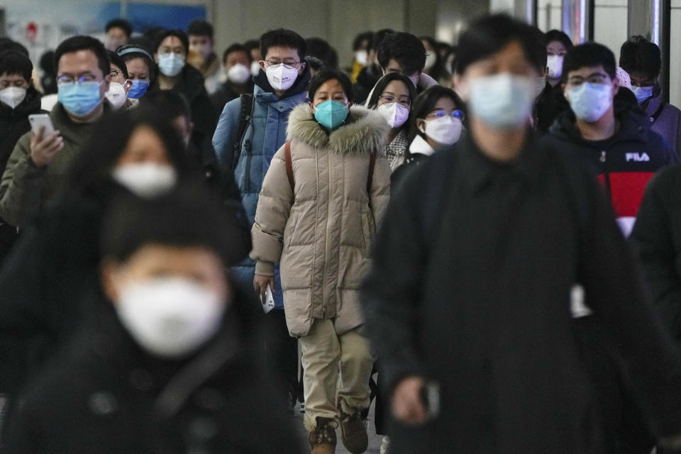 FILE - Masked commuters walk through a walkway in between two subway stations as they head to work during the morning rush hour in Beijing on Dec. 20, 2022. Japanese Prime Minister Fumio Kishida announced Tuesday, Dec. 27, that Japan will tighten border controls against COVID-19 by requiring tests for all visitors from China starting Friday as a temporary emergency measure against the surging infections there. (AP Photo/Andy Wong, File)