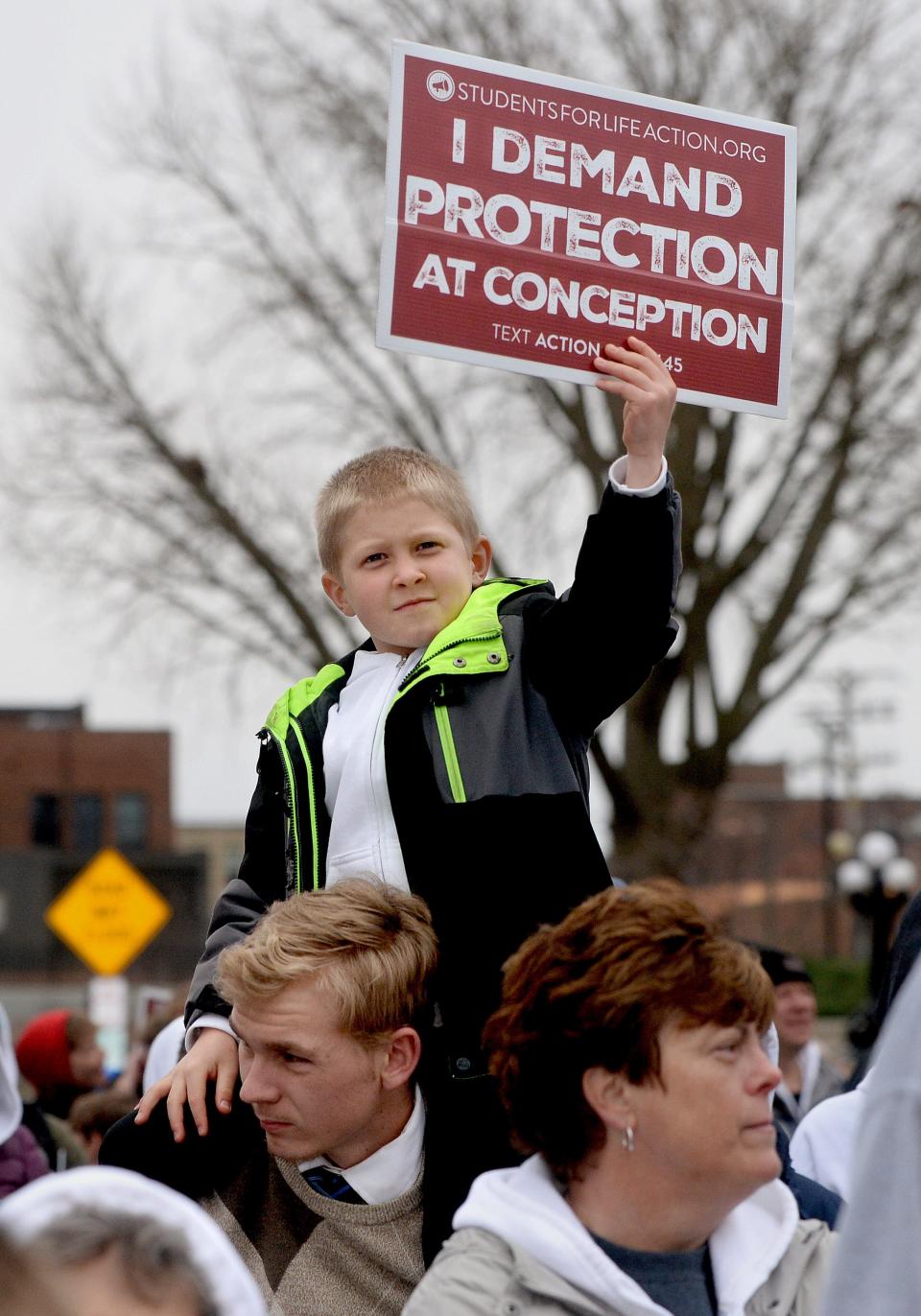 Benjamin Huber, 10, of Effingham holds up a sign as he sits on the shoulders of his cousin Virgil Jansen, also of Effingham, during the Illinois March for Life rally at the State capitol Tuesday March 21, 2023.