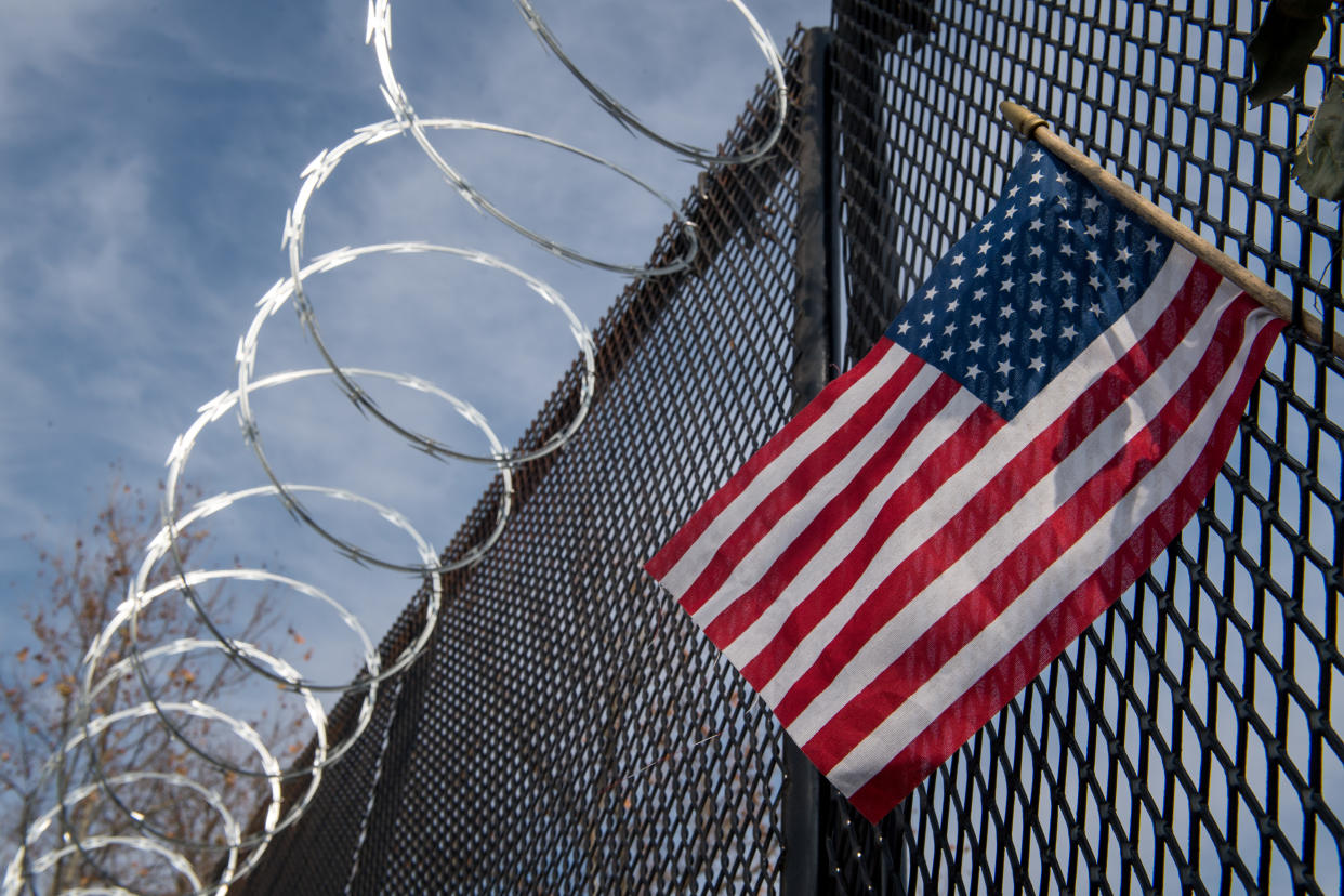 WASHINGTON, DC - JANUARY 15: An American flag along the raze wire fencing that now surrounds the US Capitol ahead of the inauguration on January 15, 2021 in Washington, DC.  After last week's Capitol Riot the FBI has warned of additional threats against the US Capitol and in all 50 states.  (Photo by Liz Lynch/Getty Images)