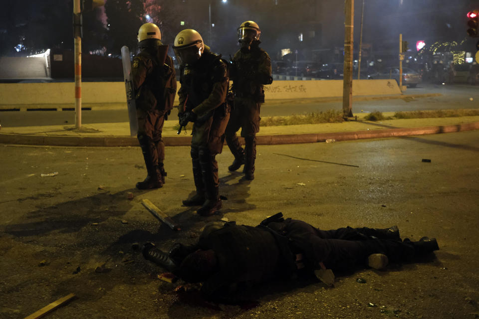 A policeman lays injured on the road after an attack by protesters during clashes in Athens, Tuesday, March 9, 2021. Severe clashes broke out Tuesday in Athens after youths protesting an incident of police violence attacked a police station with petrol bombs, and severely injured one officer. (AP Photo/Aggelos Barai)