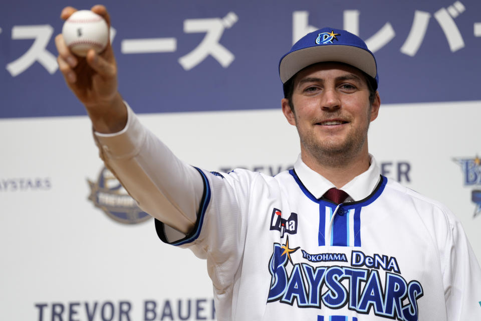 Trevor Bauer with his new uniform and cap of Yokohama DeNA BayStars poses for photographers during a photo session of the news conference Friday, March 24, 2023, in Yokohama, near Tokyo. (AP Photo/Eugene Hoshiko)