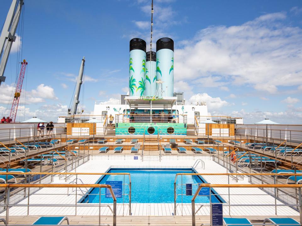 Lounge chairs surrounding a pool on a cruise ship.