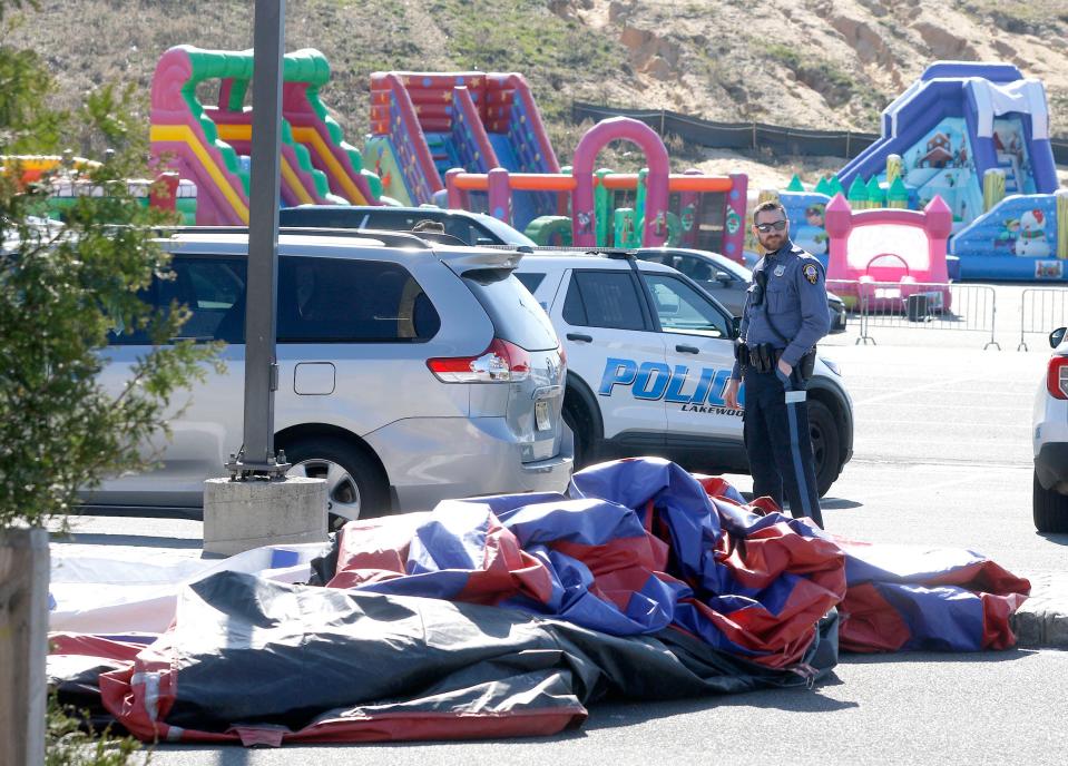 A Lakewood police officer stands by an inflatable amusement ride that broke free - injuring at least three people - during a carnival behind the Ateres Reva Hall in the Township Monday afternoon, April 10, 2023.