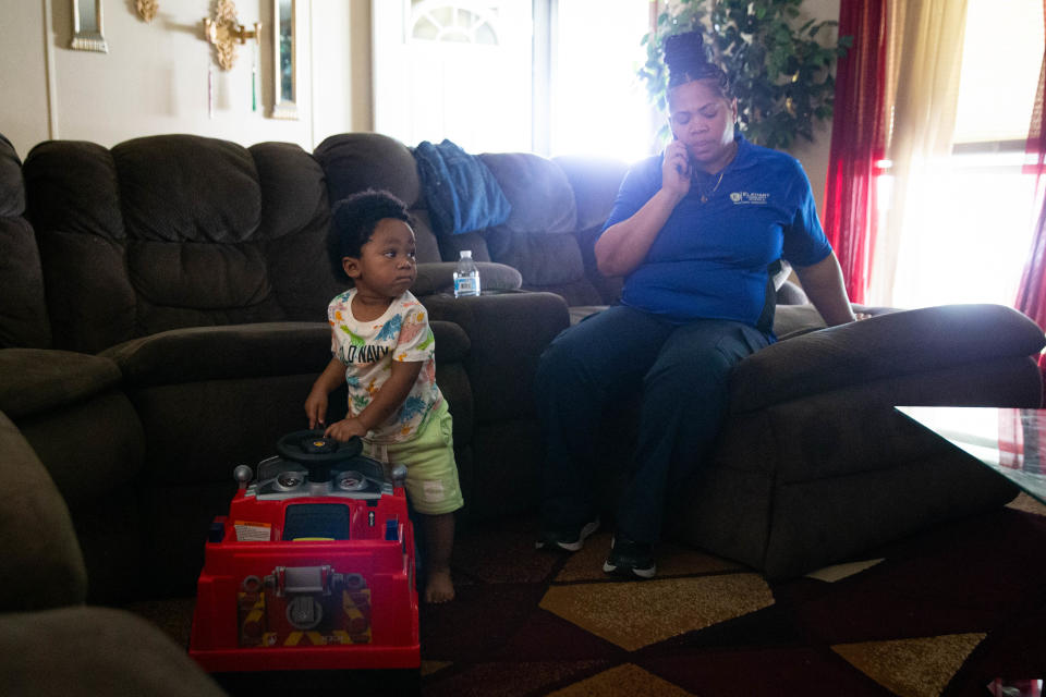 Nakia Dalton, right, talks on the phone with her incarcerated son, Deante Dalton, while Deante's 14-month-old nephew, Zadius Baker plays with a toy firetruck on Wednesday, June 12, 2024, at Nakia's home in Elkhart.