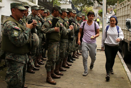 Residents walk as soldiers stand near the Electoral National Council (CNE) headquarters prior to Sunday presidential election in Quito, Ecuador, April 1, 2017. REUTERS/Mariana Bazo