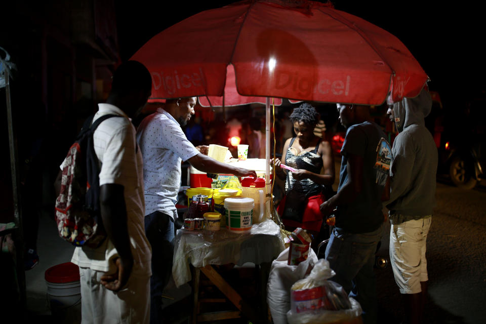 In this April 16, 2019 photo, street vendors sell juice in Petion-Ville, Haiti. The current fuel crisis is helping push Haiti's economy dangerously close to recession. (AP Photo/Dieu Nalio Chery)