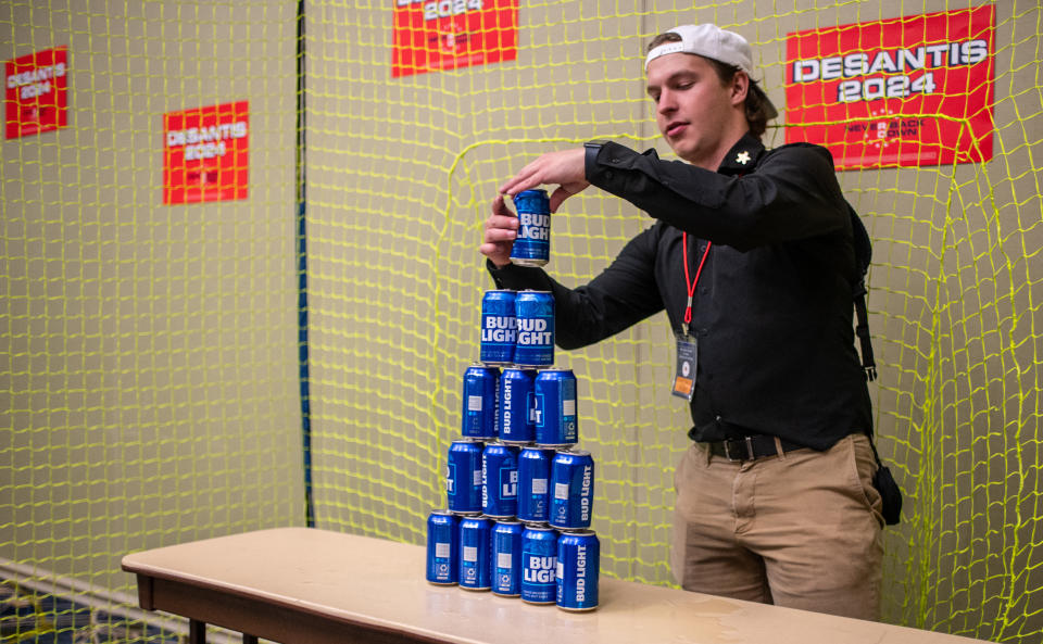 An employee builds a tower of Bud Light beer cans for ball target practice in the Ron DeSantis booth at the Republican Party of Iowa's 2023 Lincoln Dinner at the Iowa Events Center in Des Moines, Iowa, on July 28, 2023. (Photo by Sergio FLORES / AFP) (Photo by SERGIO FLORES/AFP via Getty Images)