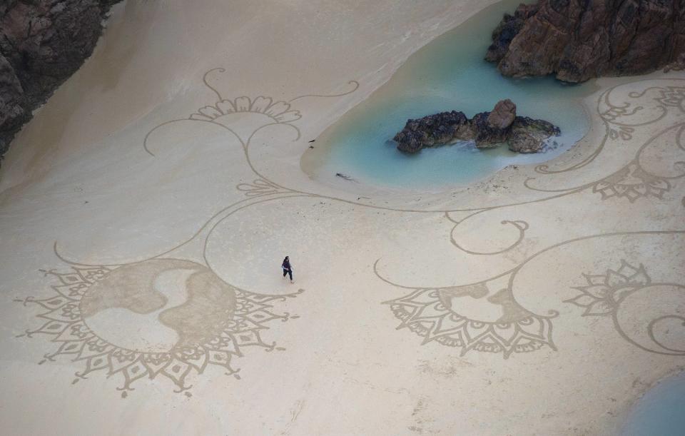 El artista Andrés Amador camina sobre una de sus obras en la playa Plemont, con la que participó en el Campeonato de Arte de Playa MyMemory.com, en Jersey, en las islas Channel. Carl Court/WENN.com