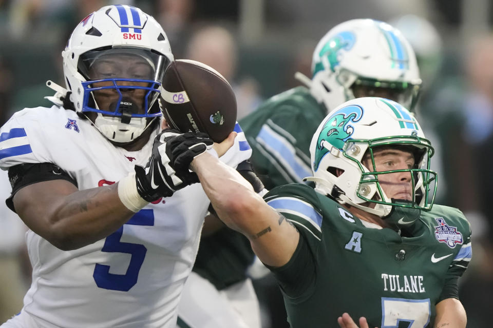 SMU defensive end Elijah Roberts (5) grabs the arm of Tulane quarterback Michael Pratt (7) during the first half of the American Athletic Conference championship NCAA college football game, Saturday, Dec. 2, 2023, in New Orleans. (AP Photo/Gerald Herbert)