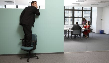 Businessman standing on chair listening to office meeting