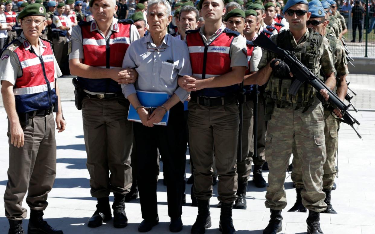 Paramilitary police and members of the special forces escort former Air Force commander Akin Ozturk and other suspects of last year's failed coup, outside the courthouse at the start of a trial in Ankara last year - AP