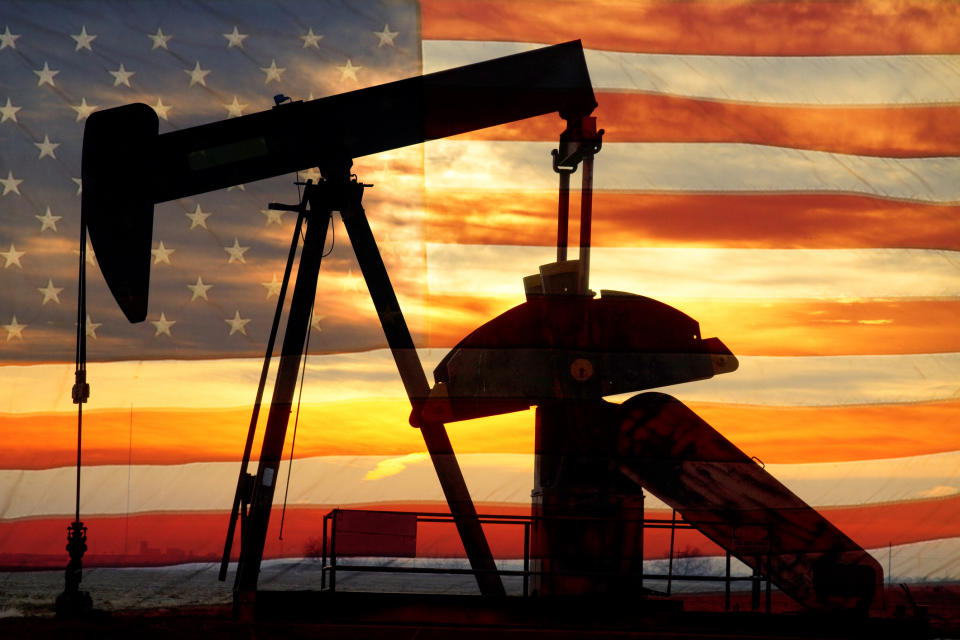 An oil pump with an American flag and sunset in the background.