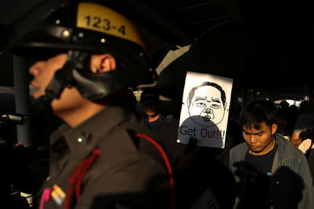 FILE PHOTO: A pro-democracy protester wearing a mask mocking Thailand's Deputy Prime Minister Prawit Wongsuwan is escorted by a police officer during a a protest in Bangkok, Thailand, February 6, 2018. Picture taken February 6, 2018. REUTERS/Athit Perawongmetha/File Photo