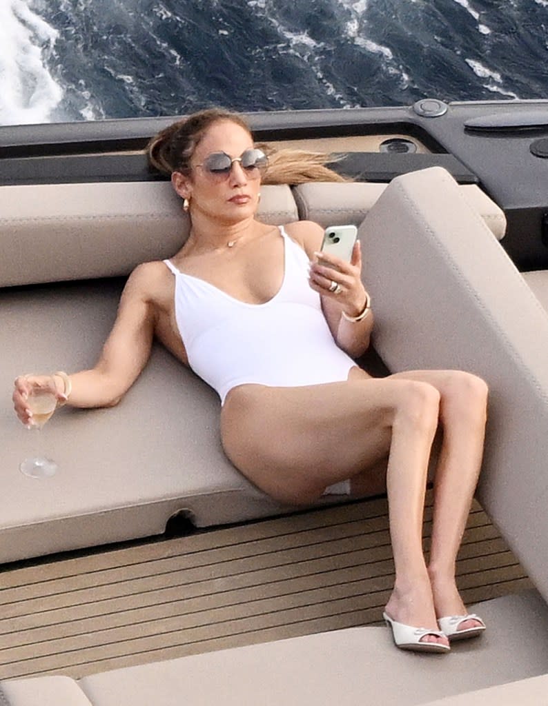 J.Lo was relaxing on a boat in Italy, looking at her phone. COBRA TEAM / BACKGRID