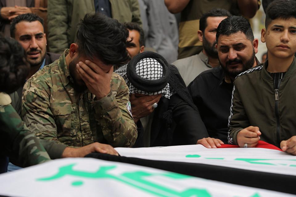 Mourners and militia fighters mourn by the flag-draped coffins of two fighters of the Popular Mobilization Forces who were killed during the US attack on against militants in Iraq, during their funeral procession at the Imam Ali shrine in Najaf, Iraq, Saturday, March 14, 2020. The U.S. launched airstrikes on Thursday in Iraq, targeting the Iranian-backed Shiite militia members believed responsible for a rocket attack that killed and wounded American and British troops at a base north of Baghdad. (AP Photo/Anmar Khalil)