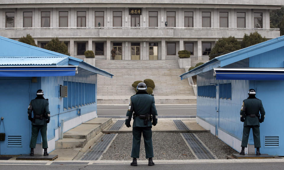 FILE - In this March 12, 2014, file photo, a North Korean soldier, center top, looks at the southern side as three South Korean soldiers guard at the border village of Panmunjom, which has separated the two Koreas since the Korean War, in Paju, South Korea. North Korea said Friday, Nov. 16, 2018, that it will deport an American citizen it detained for illegally entering the country recently, as the country's state media said leader Kim Jong Un supervised a test of a newly developed high-tech weapon in an apparent bid to employ pressure on Washington and Seoul. (AP Photo/Lee Jin-man, File)