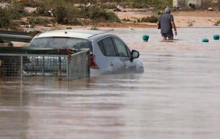 A man wades through a flooded street after heavy rains in San Javier