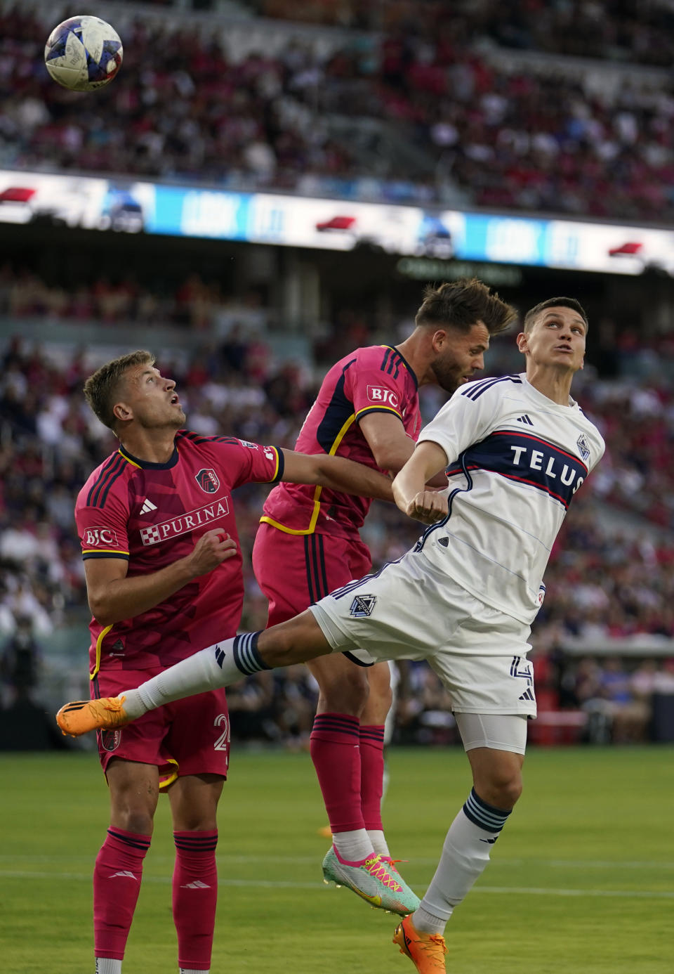 Vancouver Whitecaps' Ranko Veselinovic, right, heads the ball as St. Louis City's Eduard Lowen and Lucas Bartlett, left, defend during the first half of an MLS soccer match Saturday, May 27, 2023, in St. Louis. (AP Photo/Jeff Roberson)