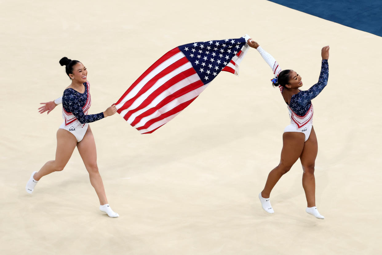 PARIS, FRANCE - JULY 30: Sunisa Lee (L) and Jordan Chiles (R) of Team United States celebrate with the national flag after winning the gold medals during the Artistic Gymnastics Women's Team Final on day four of the Olympic Games Paris 2024 at Bercy Arena on July 30, 2024 in Paris, France. (Photo by Patrick Smith/Getty Images)