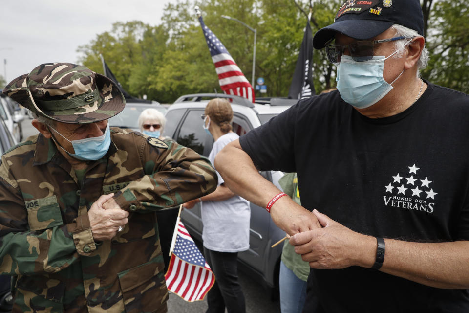 Joe Torre, 75, left, and Kicky Clavell, 67, greet one another as their motorcade stops outside the VA Medical Center before a wreath laying ceremony, Monday, May 25, 2020, in the Brooklyn borough of New York. (AP Photo/John Minchillo)