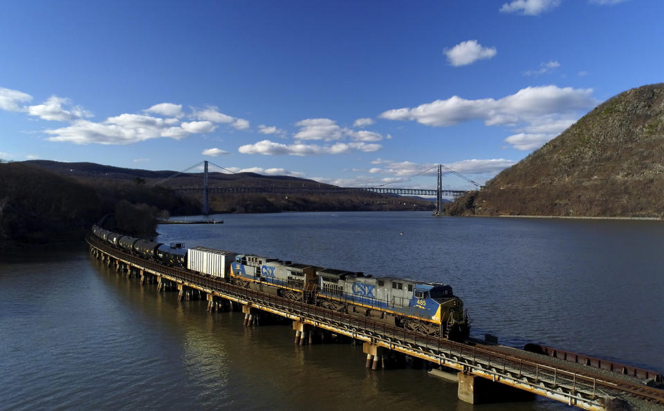 FILE - In this April 26, 2018, file photo a CSX Transportation locomotive pulls a train of tank cars across a bridge on the Hudson River along the edge of Bear Mountain State Park near Fort Montgomery, N.Y. This year’s scheduled completion of a $15 billion automatic railroad braking system will bolster the industry’s argument for eliminating one of the two crew members in most locomotives. But labor groups argue that single-person crews would make trains more accident prone. (AP Photo/Julie Jacobson, File)