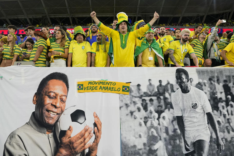 Brazil supporters cheer on the stands above a banner with pictures of soccer legend Pele, while waiting for the start of the World Cup round of 16 soccer match between Brazil and South Korea, at the Education City Stadium in Al Rayyan, Qatar, Monday, Dec. 5, 2022. (AP Photo/Martin Meissner)