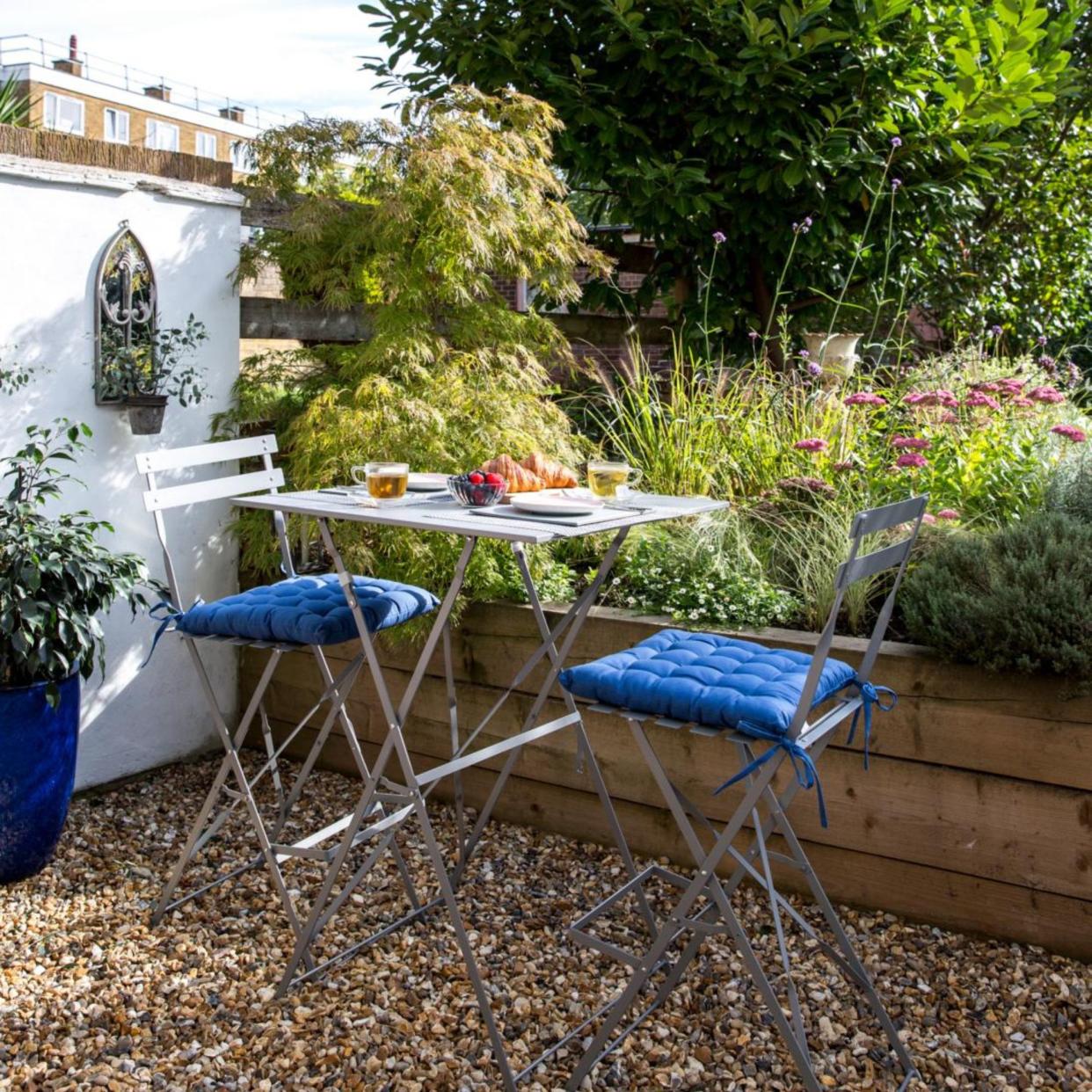  Patio courtyard with potted plants and bistro set. 